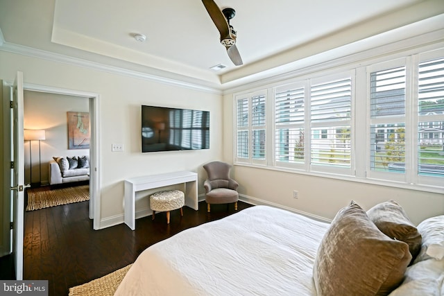 bedroom with crown molding, ceiling fan, a tray ceiling, and dark hardwood / wood-style flooring