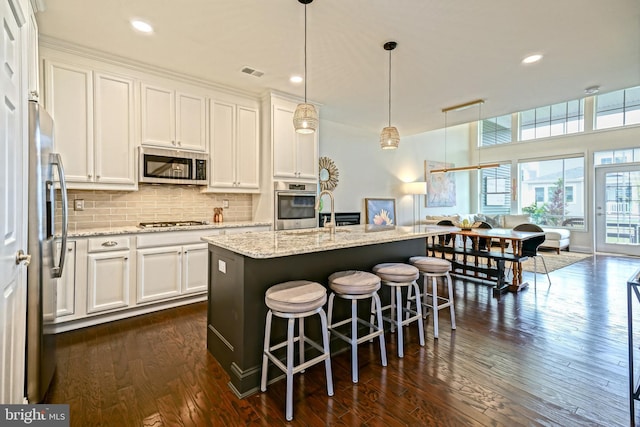 kitchen featuring stainless steel appliances, white cabinetry, decorative backsplash, and dark wood-style floors