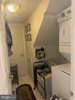 laundry area featuring light tile patterned flooring and stacked washer and clothes dryer