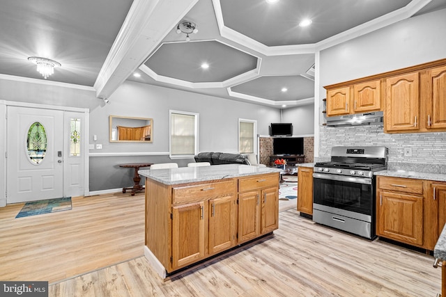 kitchen featuring crown molding, stainless steel gas range, light stone counters, a kitchen island, and decorative backsplash