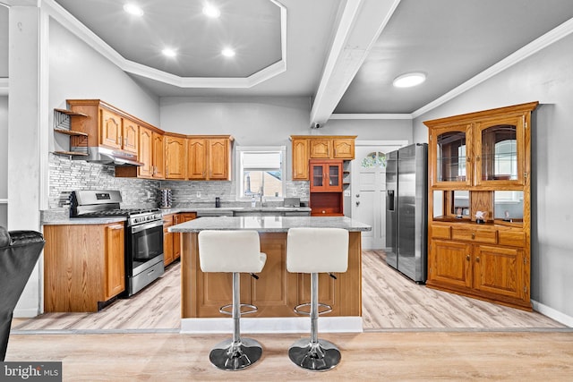 kitchen featuring a breakfast bar area, tasteful backsplash, a center island, appliances with stainless steel finishes, and light hardwood / wood-style floors