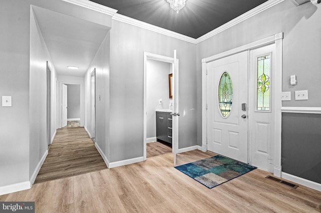 entrance foyer featuring crown molding and light hardwood / wood-style flooring