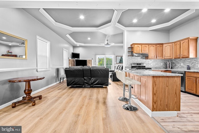 kitchen with tasteful backsplash, light hardwood / wood-style flooring, appliances with stainless steel finishes, a kitchen breakfast bar, and a kitchen island