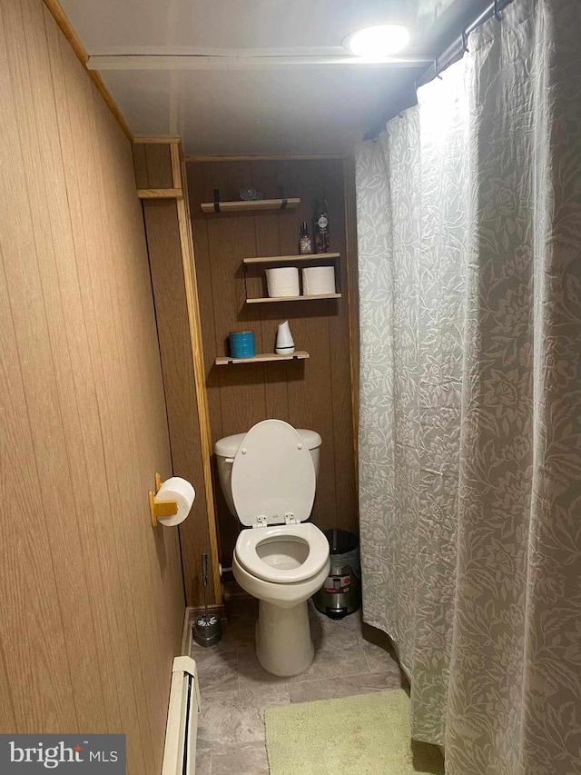 bathroom with tile patterned flooring, wooden walls, and a baseboard heating unit