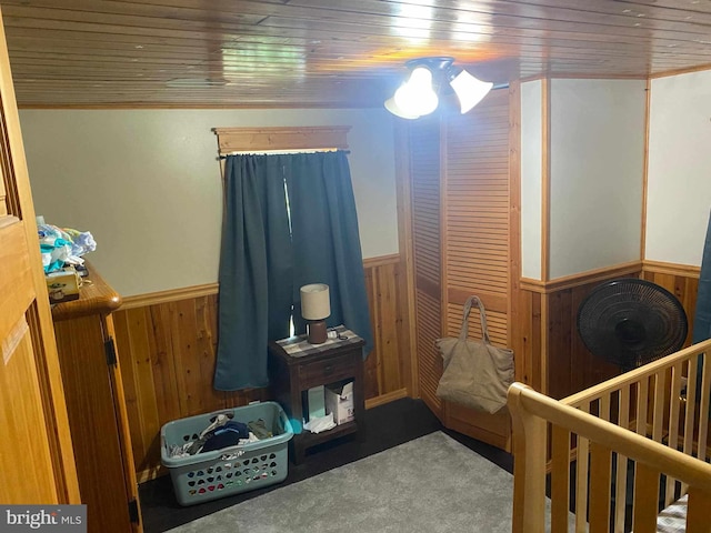 bedroom featuring wooden ceiling, a crib, carpet floors, and wood walls