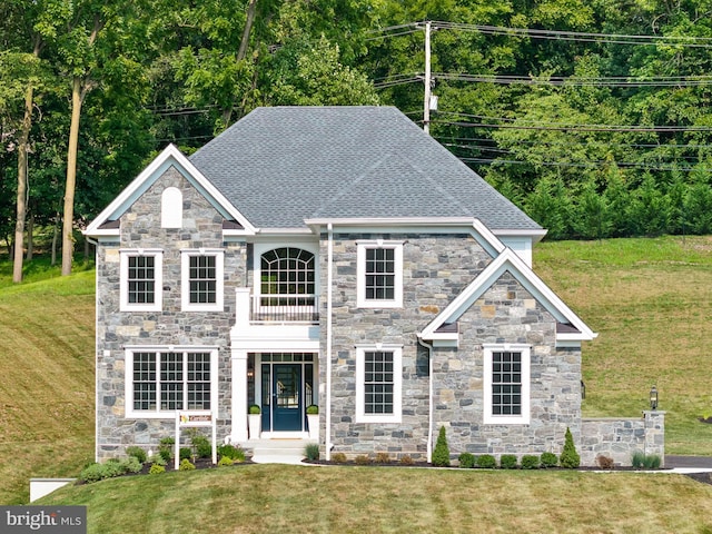 view of front facade with a balcony and a front yard