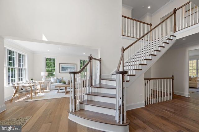 staircase featuring hardwood / wood-style floors, crown molding, and a towering ceiling