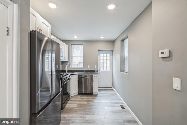 kitchen with white cabinetry, appliances with stainless steel finishes, light hardwood / wood-style floors, and sink