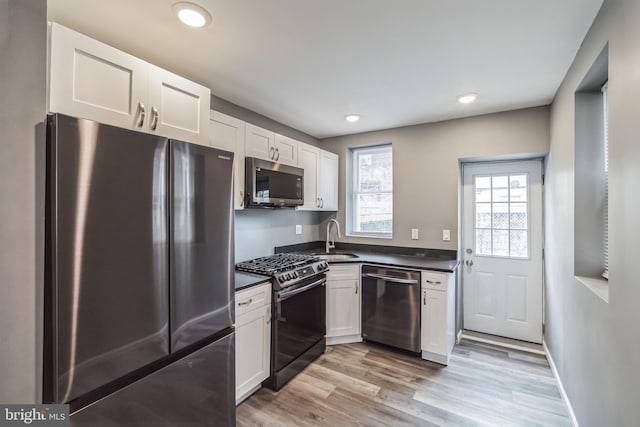 kitchen featuring light wood-type flooring, appliances with stainless steel finishes, sink, and white cabinets