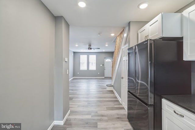 kitchen with ceiling fan, light wood-type flooring, white cabinets, and black fridge