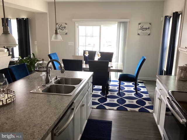 kitchen with stainless steel appliances, decorative light fixtures, sink, white cabinets, and dark hardwood / wood-style flooring