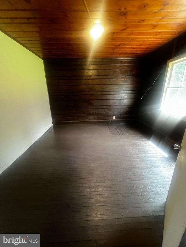 empty room with dark wood-type flooring, wooden ceiling, and vaulted ceiling