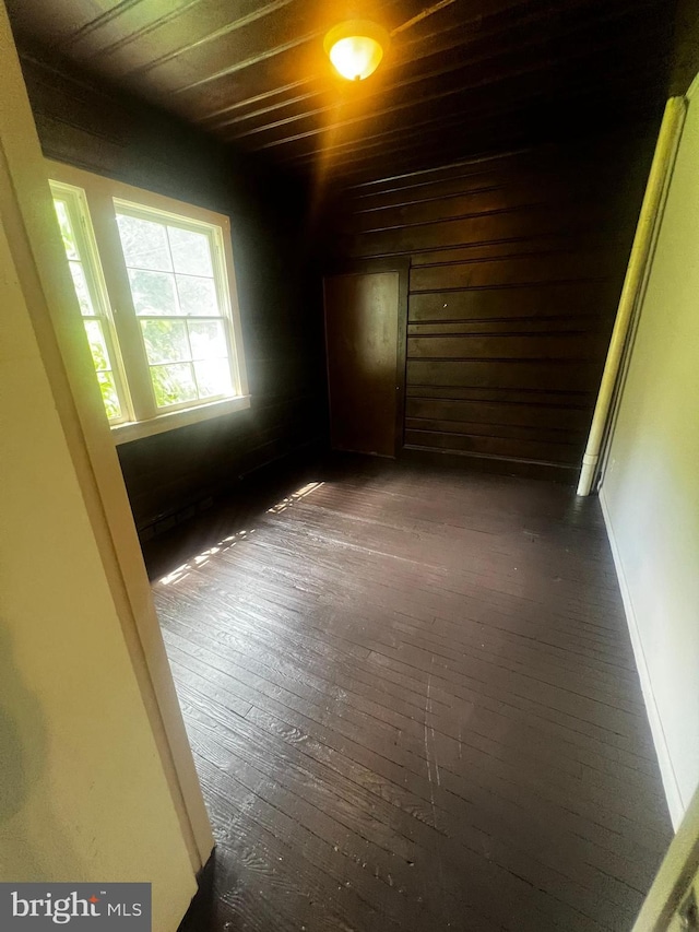 empty room with dark hardwood / wood-style floors and wood ceiling