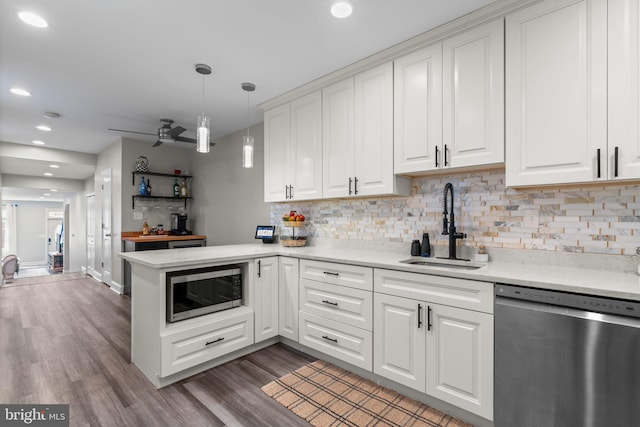 kitchen featuring sink, hanging light fixtures, kitchen peninsula, stainless steel appliances, and white cabinets