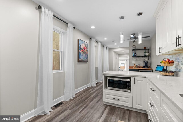 kitchen featuring backsplash, white cabinets, light stone counters, and decorative light fixtures