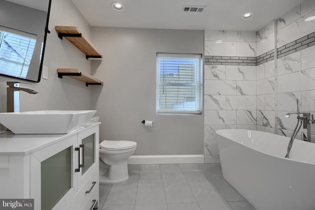 bathroom featuring vanity, a washtub, and toilet