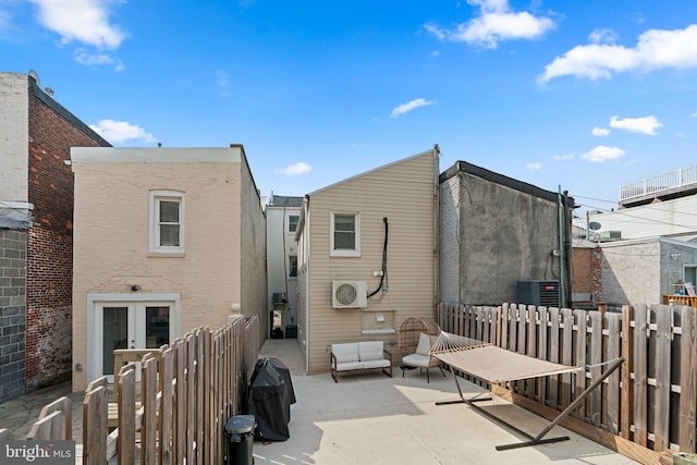 rear view of house with central AC unit, a patio area, and french doors