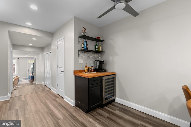 bar with butcher block counters, wine cooler, ceiling fan, and hardwood / wood-style flooring