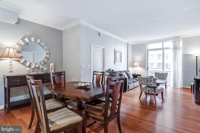 dining space featuring baseboards, wood finished floors, and crown molding