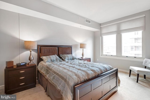 bedroom with baseboards, visible vents, and light colored carpet