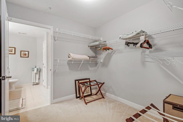 walk in closet with carpet flooring, visible vents, and tile patterned floors