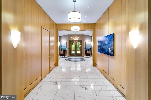 hall with marble finish floor, wooden walls, and french doors