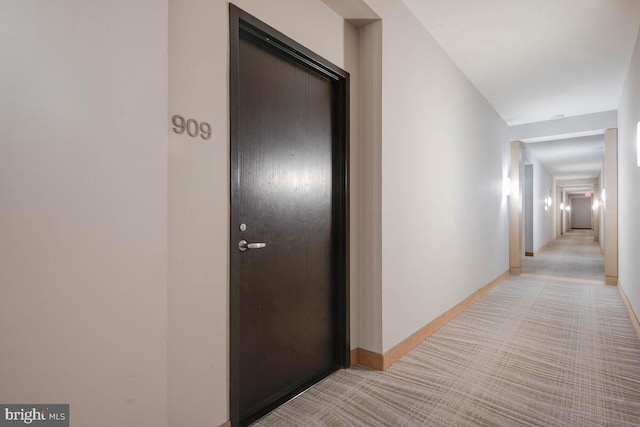 hall featuring baseboards and light colored carpet