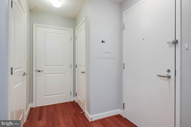 hallway featuring electric panel, baseboards, and dark wood finished floors