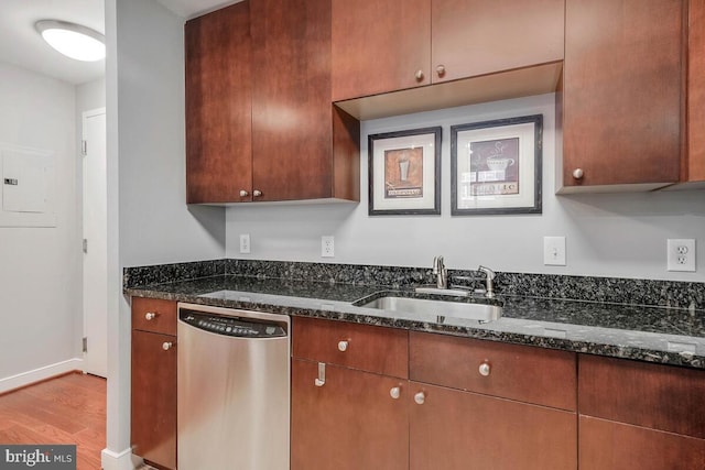 kitchen featuring electric panel, dark stone counters, dishwasher, wood finished floors, and a sink