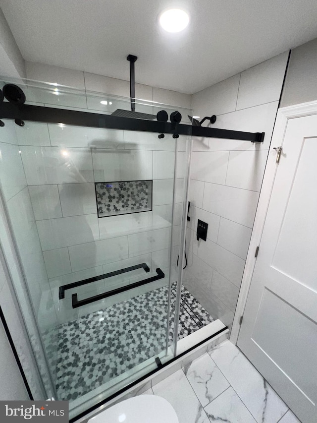 bathroom featuring a shower with door and toilet