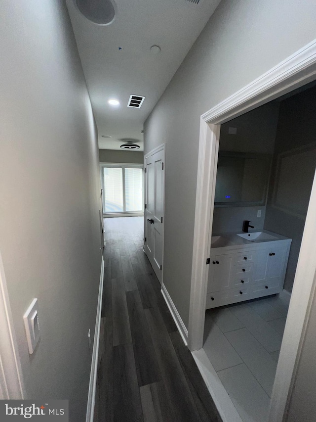 corridor with dark hardwood / wood-style flooring and sink