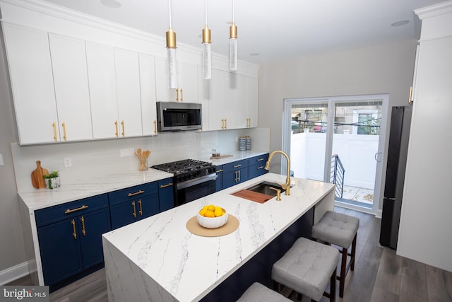 kitchen featuring an island with sink, white cabinetry, dark hardwood / wood-style floors, pendant lighting, and stainless steel appliances