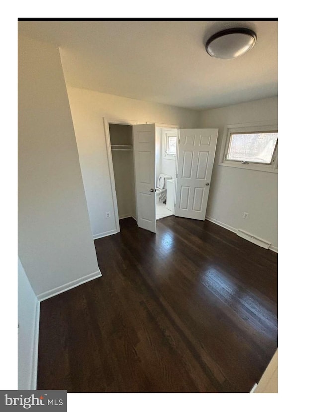 unfurnished bedroom with a closet and dark hardwood / wood-style floors