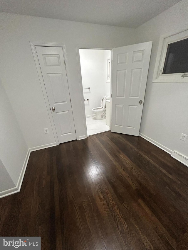 unfurnished bedroom with dark hardwood / wood-style flooring and connected bathroom