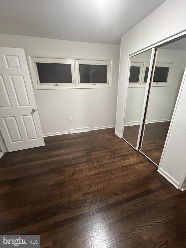 unfurnished bedroom featuring a closet and dark wood-type flooring