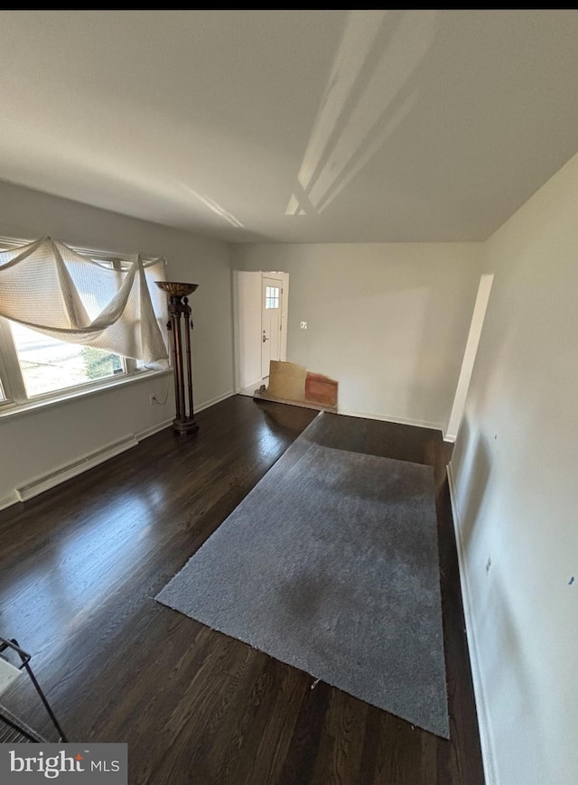 spare room with dark hardwood / wood-style flooring and a baseboard heating unit