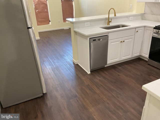 kitchen with sink, dark wood-type flooring, appliances with stainless steel finishes, white cabinetry, and kitchen peninsula