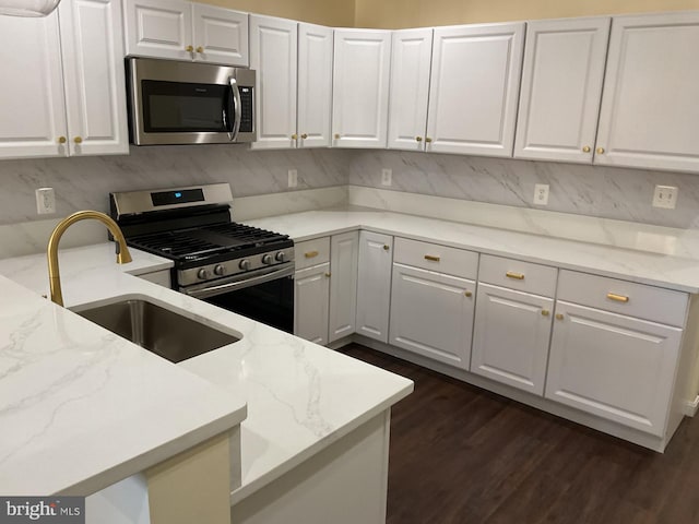 kitchen with sink, white cabinetry, stainless steel appliances, light stone countertops, and dark hardwood / wood-style flooring