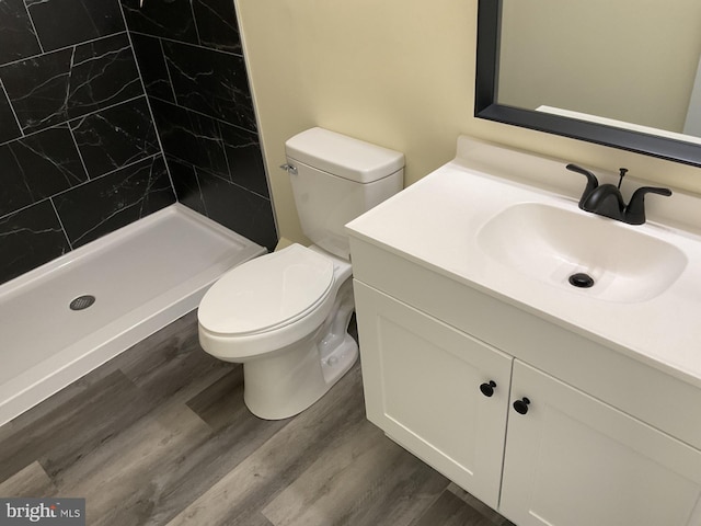 bathroom with vanity, hardwood / wood-style flooring, toilet, and tiled shower