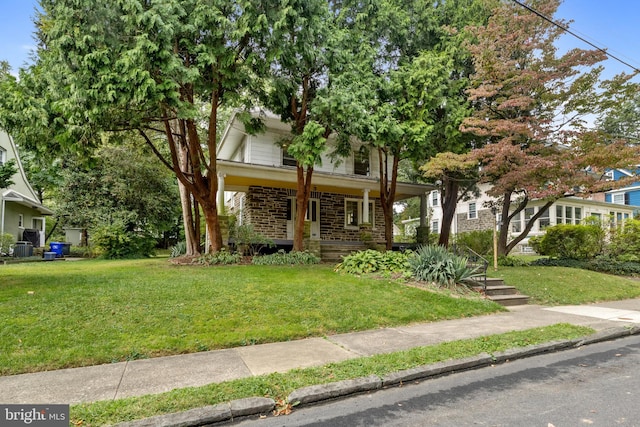 view of property hidden behind natural elements featuring a front lawn and covered porch