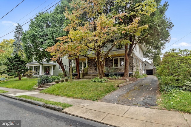 view of property hidden behind natural elements with a porch and a front lawn