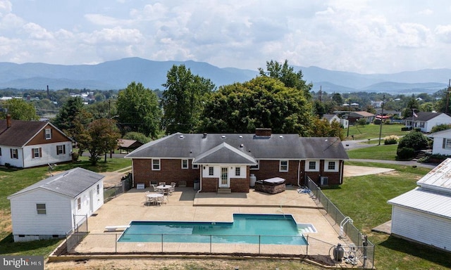 rear view of house featuring a patio area, an outbuilding, a mountain view, a yard, and a fenced in pool