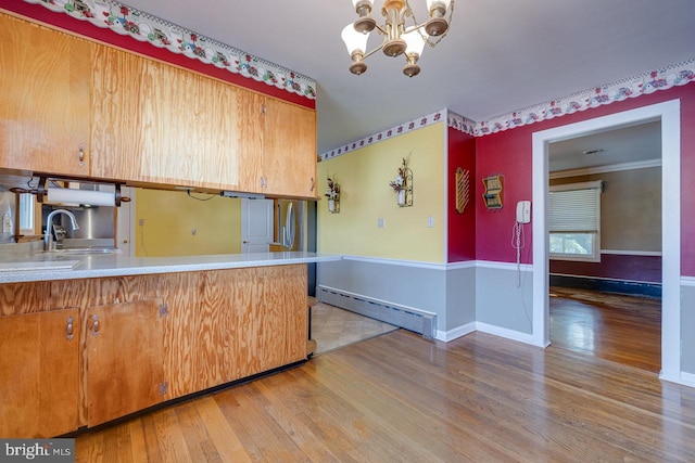 kitchen with crown molding, a chandelier, wood-type flooring, a baseboard radiator, and kitchen peninsula