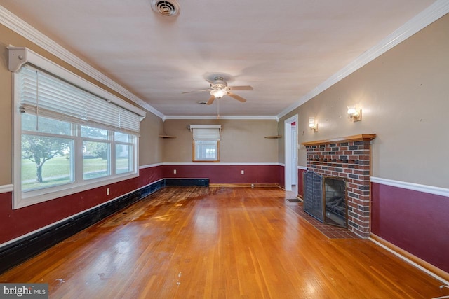 unfurnished living room with crown molding, ceiling fan, hardwood / wood-style floors, and a brick fireplace