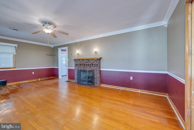 unfurnished living room featuring a fireplace, crown molding, hardwood / wood-style flooring, and ceiling fan