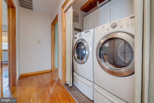 washroom featuring wood-type flooring, cabinets, and washing machine and clothes dryer