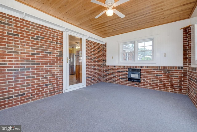 unfurnished sunroom featuring ceiling fan, a wood stove, and wooden ceiling