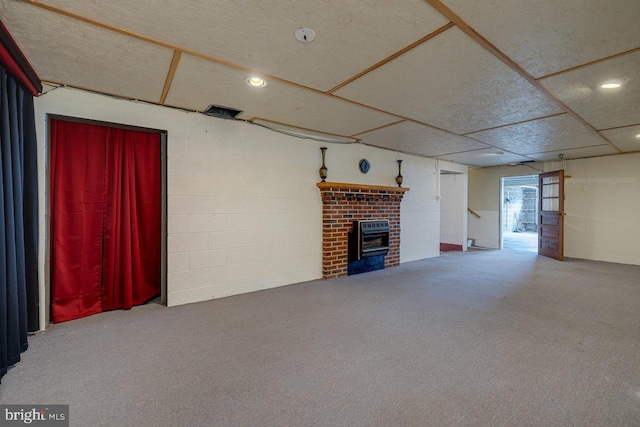 unfurnished living room featuring carpet flooring, a brick fireplace, and a drop ceiling