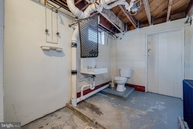 bathroom with toilet, sink, radiator heating unit, and concrete flooring