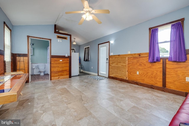 unfurnished bedroom featuring ceiling fan, white refrigerator, lofted ceiling, ensuite bathroom, and light tile patterned flooring